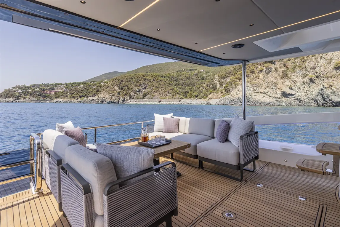 Luxury yacht deck with modern furnishings, offering stunning sea views and a glass set on a wooden table.